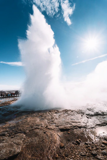 A vibrant sunrise over Yellowstone's iconic Old Faithful geyser erupting against a clear blue sky.