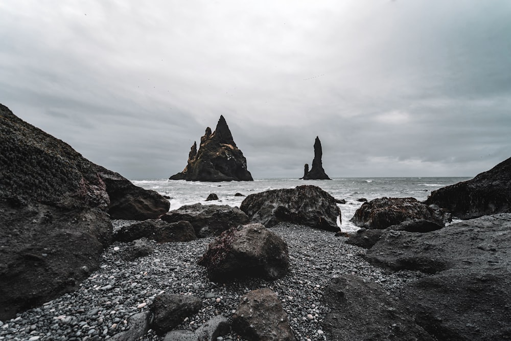 a rocky beach with a rock formation in the background