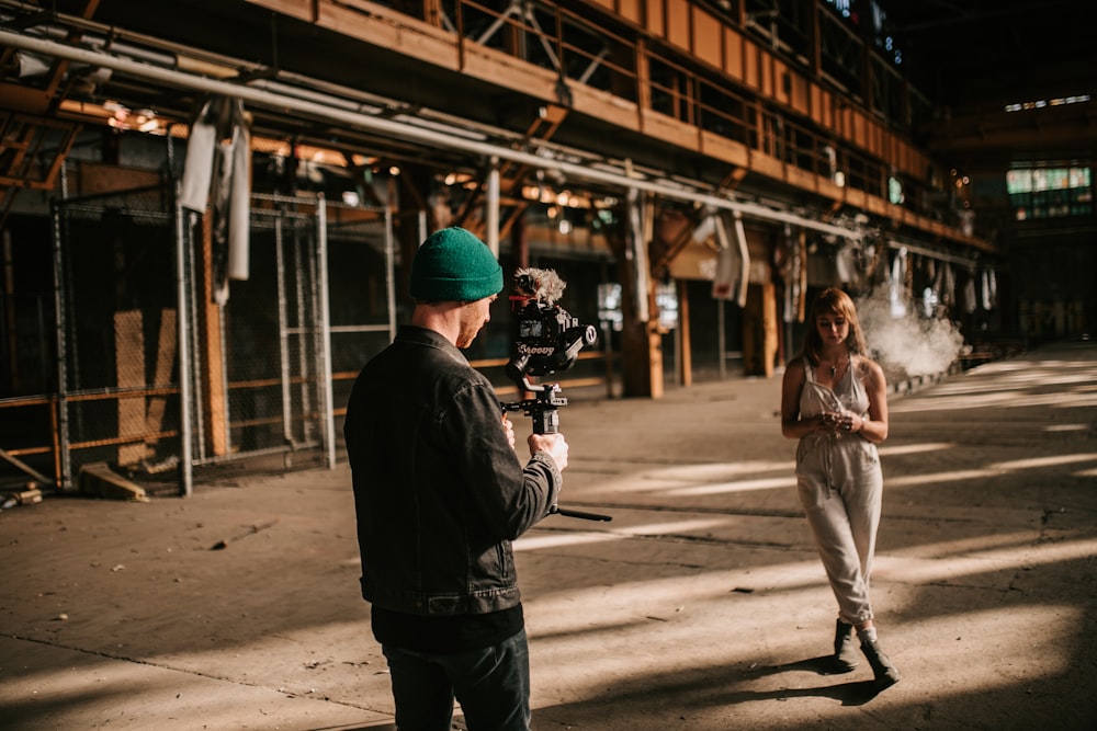 a man is filming a woman in a green hat