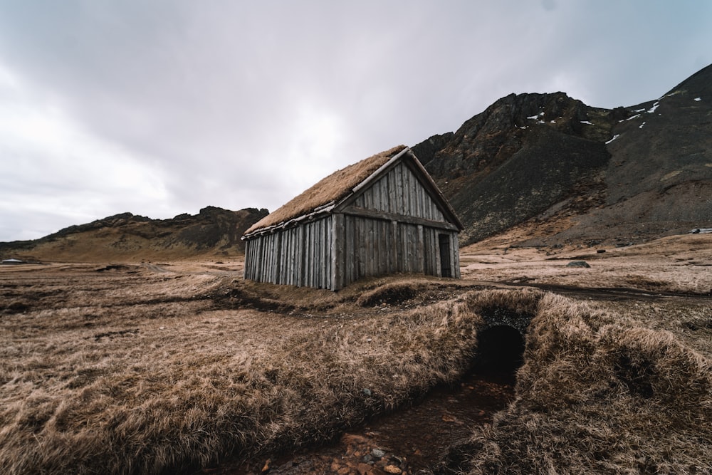 a small hut in a field with mountains in the background