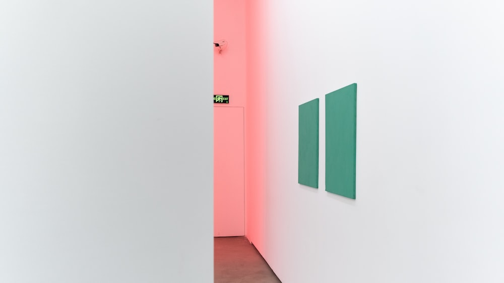 a white room with a pink wall and a green painting on the wall