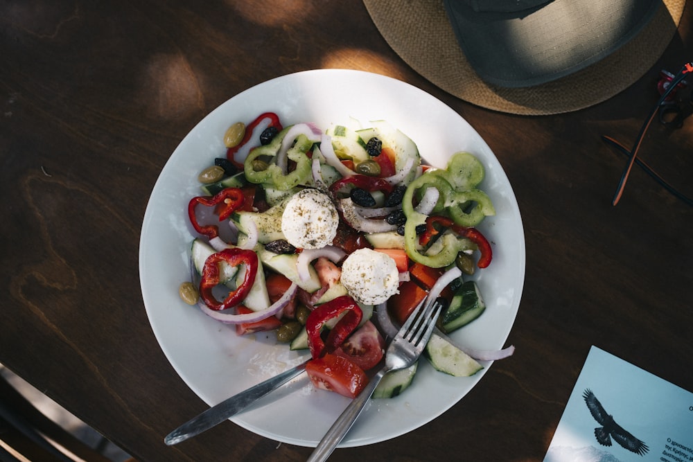 a white plate topped with a salad and a fork