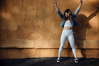 a woman celebrating weight loss success in front of brown wall