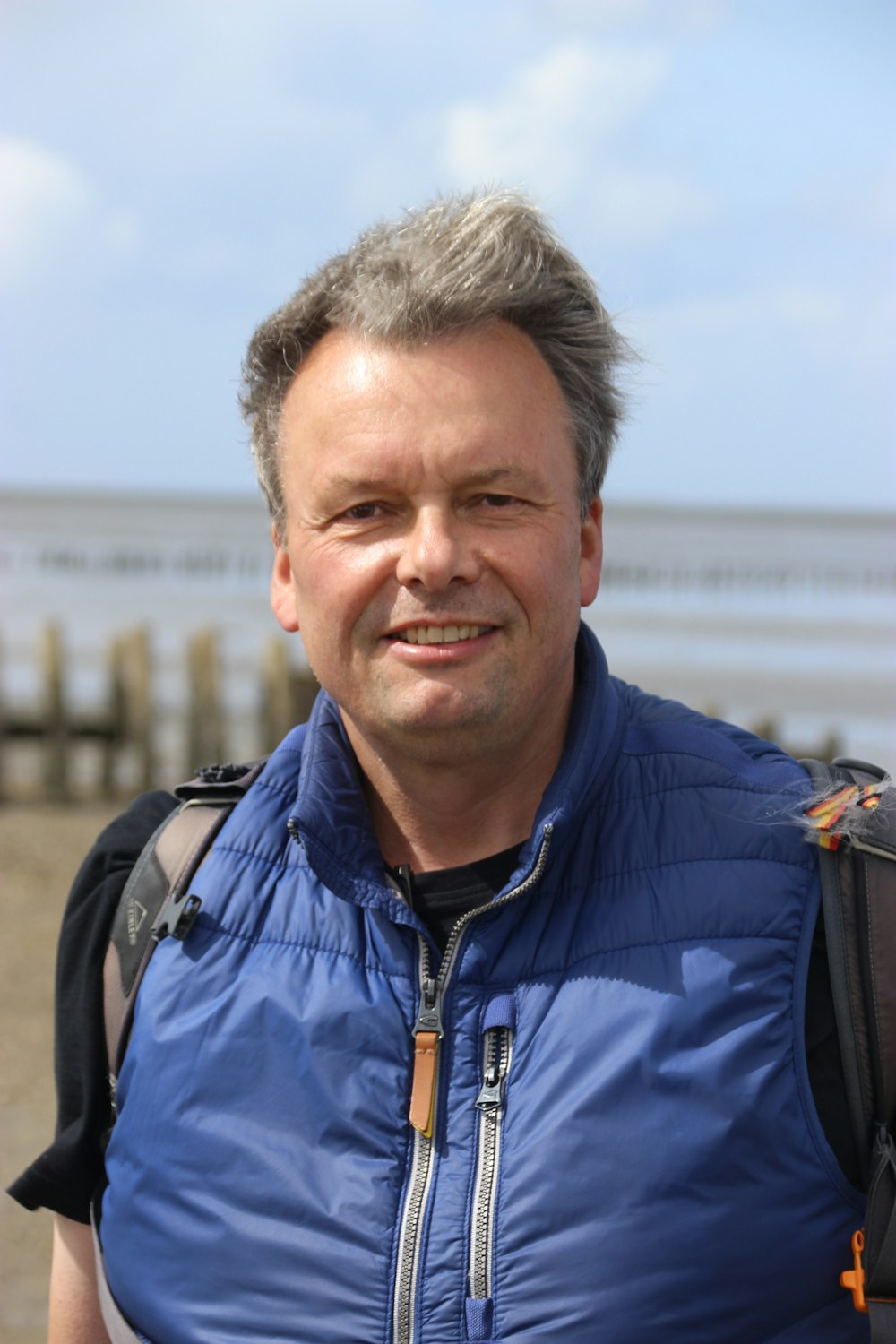 a man wearing a blue vest and a backpack