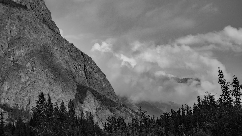 a black and white photo of a mountain with clouds