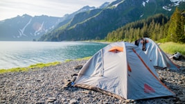 a tent pitched up on the shore of a lake