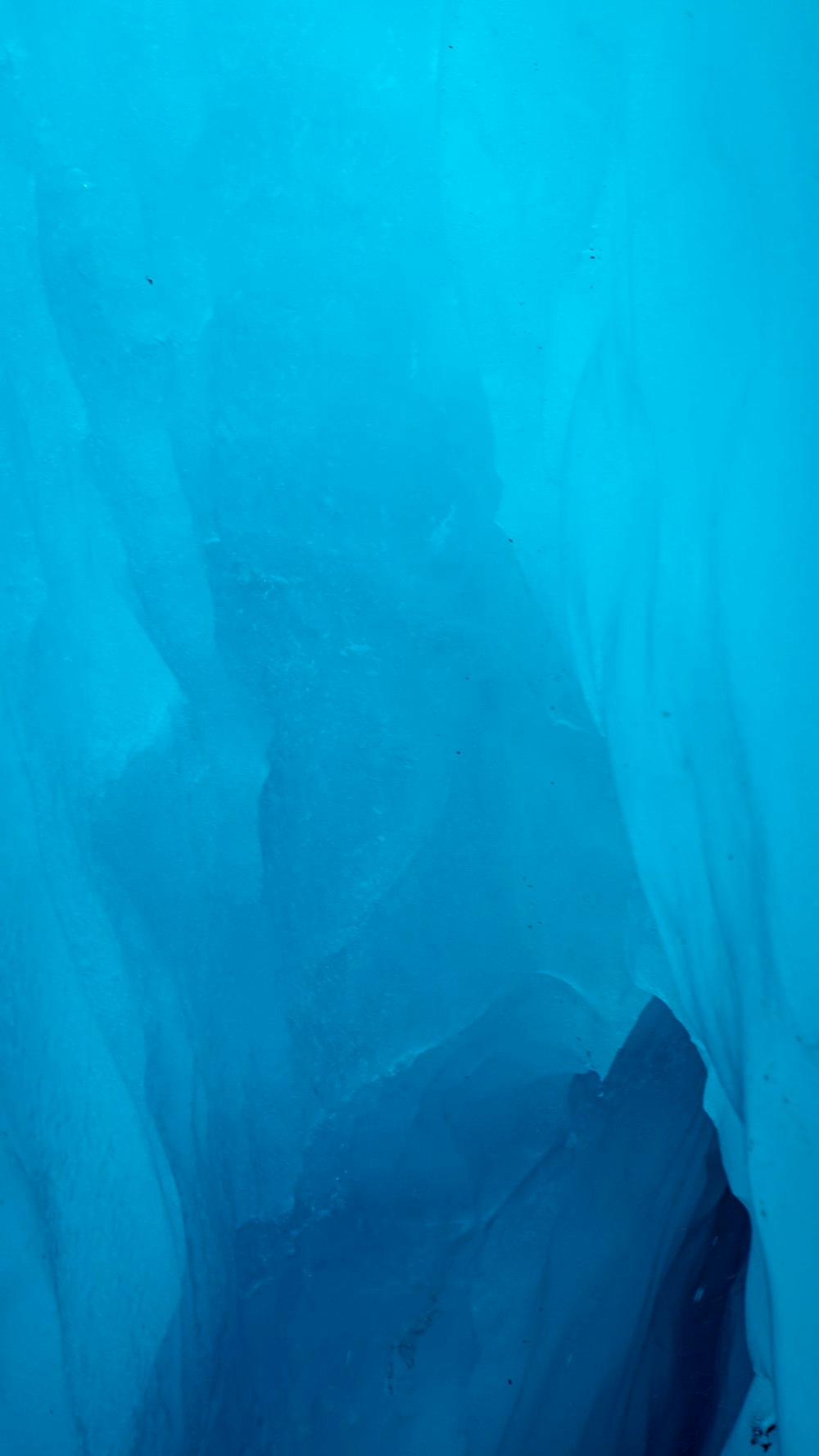 푸른 얼음 동굴에 서 있는 잠수복을 입은 남자