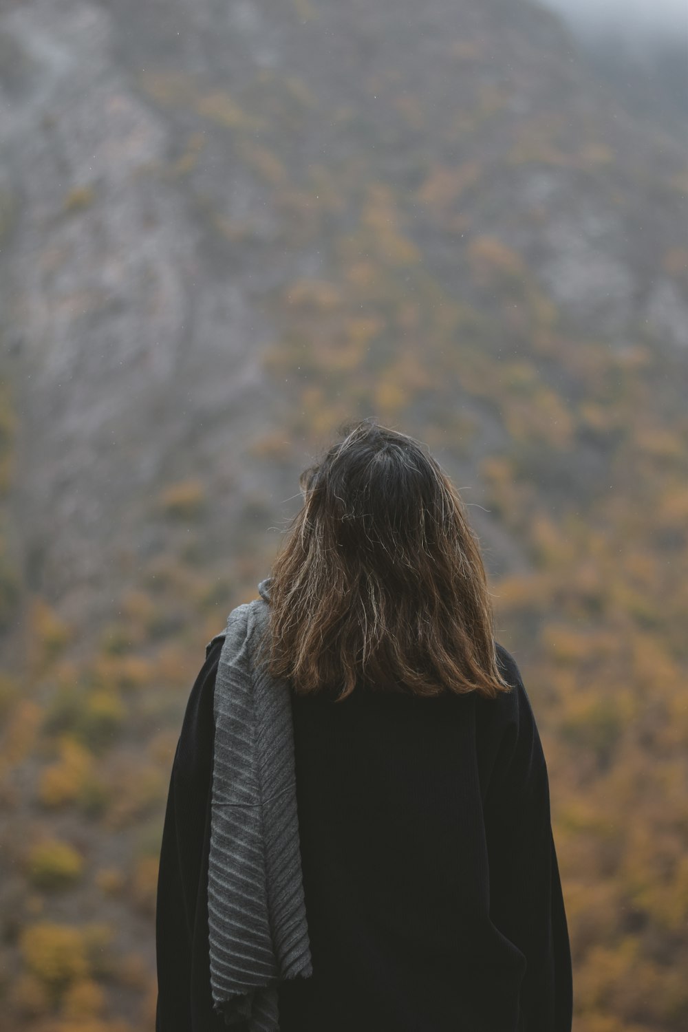 Eine Person mit langen Haaren steht vor einem Berg