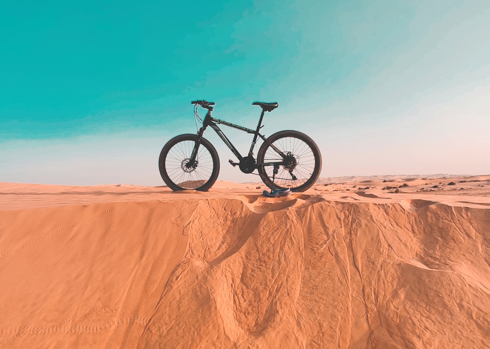 a mountain bike sitting on top of a sandy hill