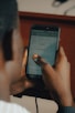 Close-up of hands typing messages on a smartphone with chat bubbles visible on the screen.