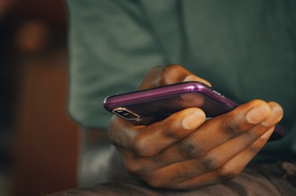 Close-up of hands typing on a smartphone with thaboombox.com live chat open, purple and gold accents visible.
