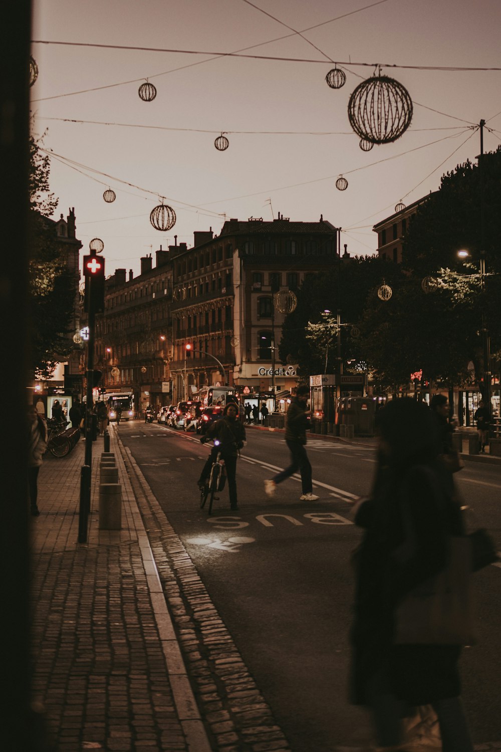 a group of people walking down a street next to tall buildings