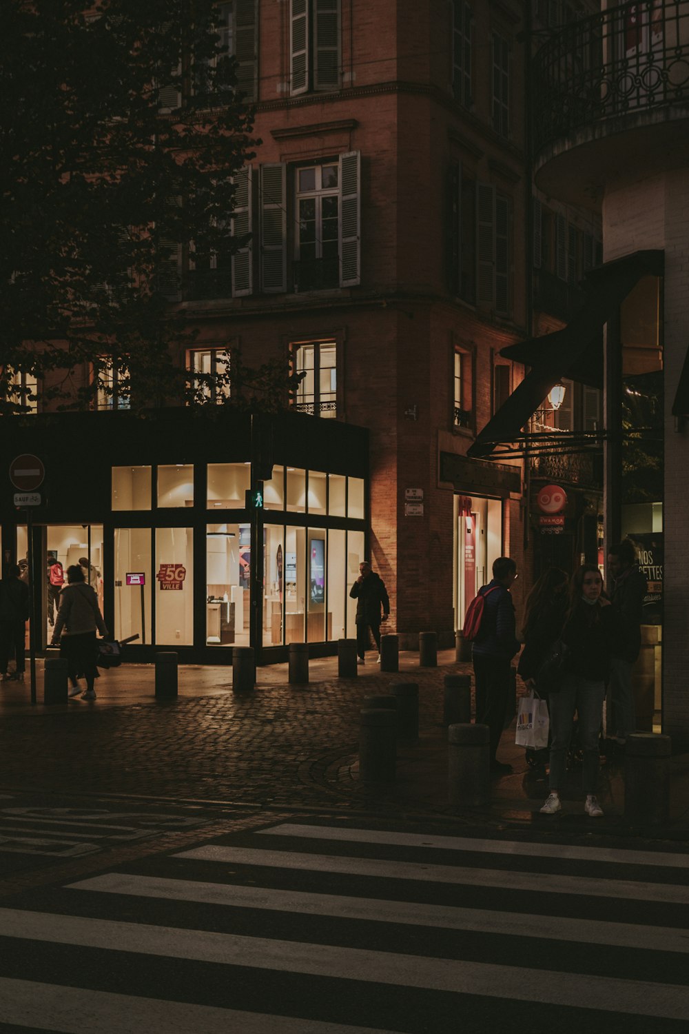 un groupe de personnes debout à l’extérieur d’un bâtiment la nuit