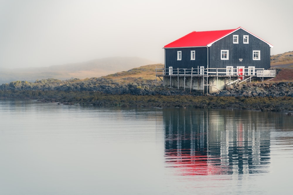 a house sitting on top of a hill next to a body of water