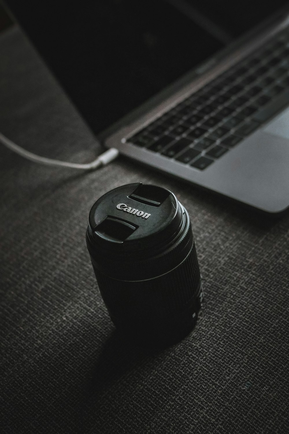 a camera lens sitting next to a laptop computer