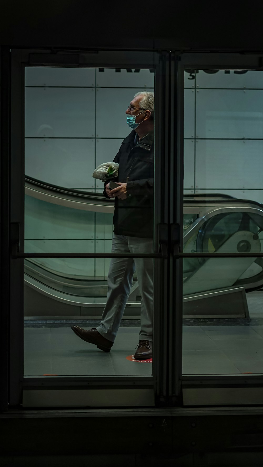 a man in a black jacket walking past a train