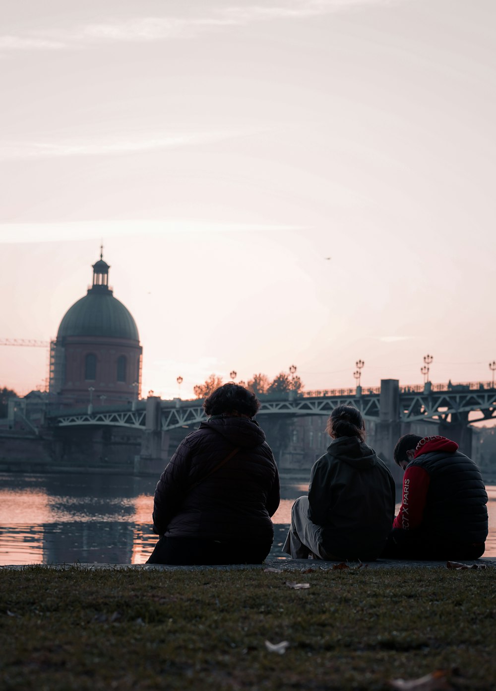 a couple of people sitting on top of a grass covered field