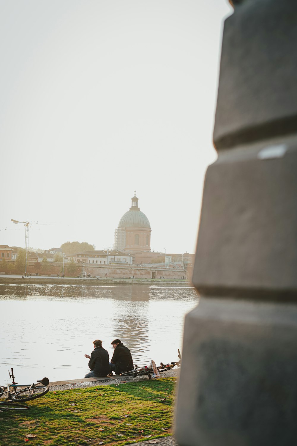 a couple of people sitting on a bench next to a body of water