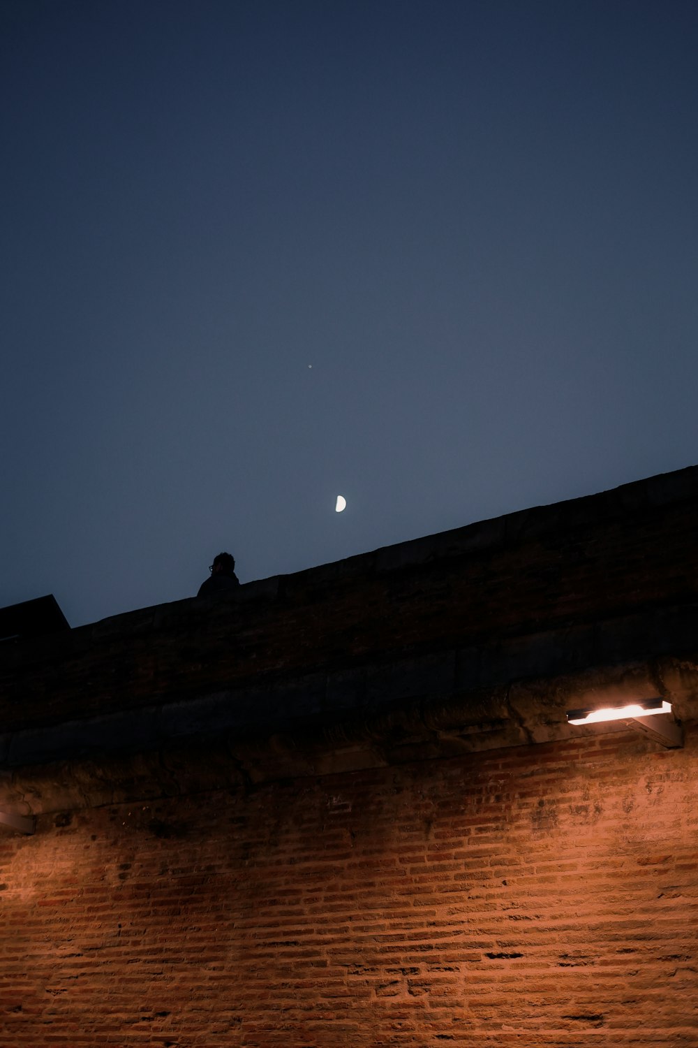 the moon is seen over a brick wall