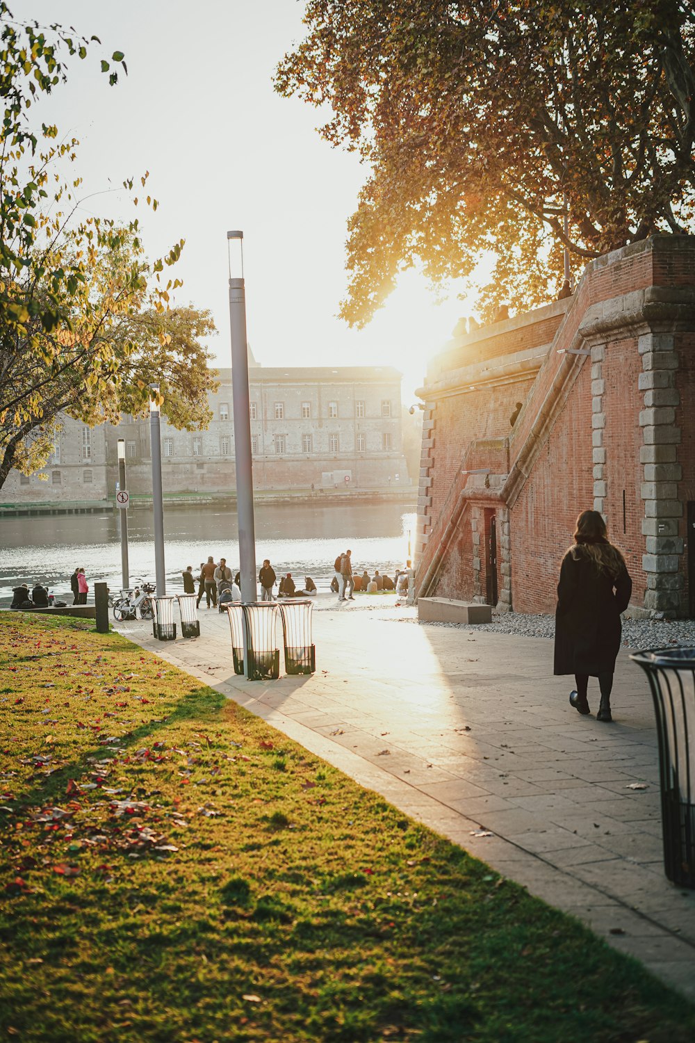 a woman walking down a sidewalk next to a river