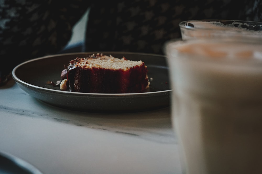 um pedaço de bolo em um prato ao lado de um copo de leite