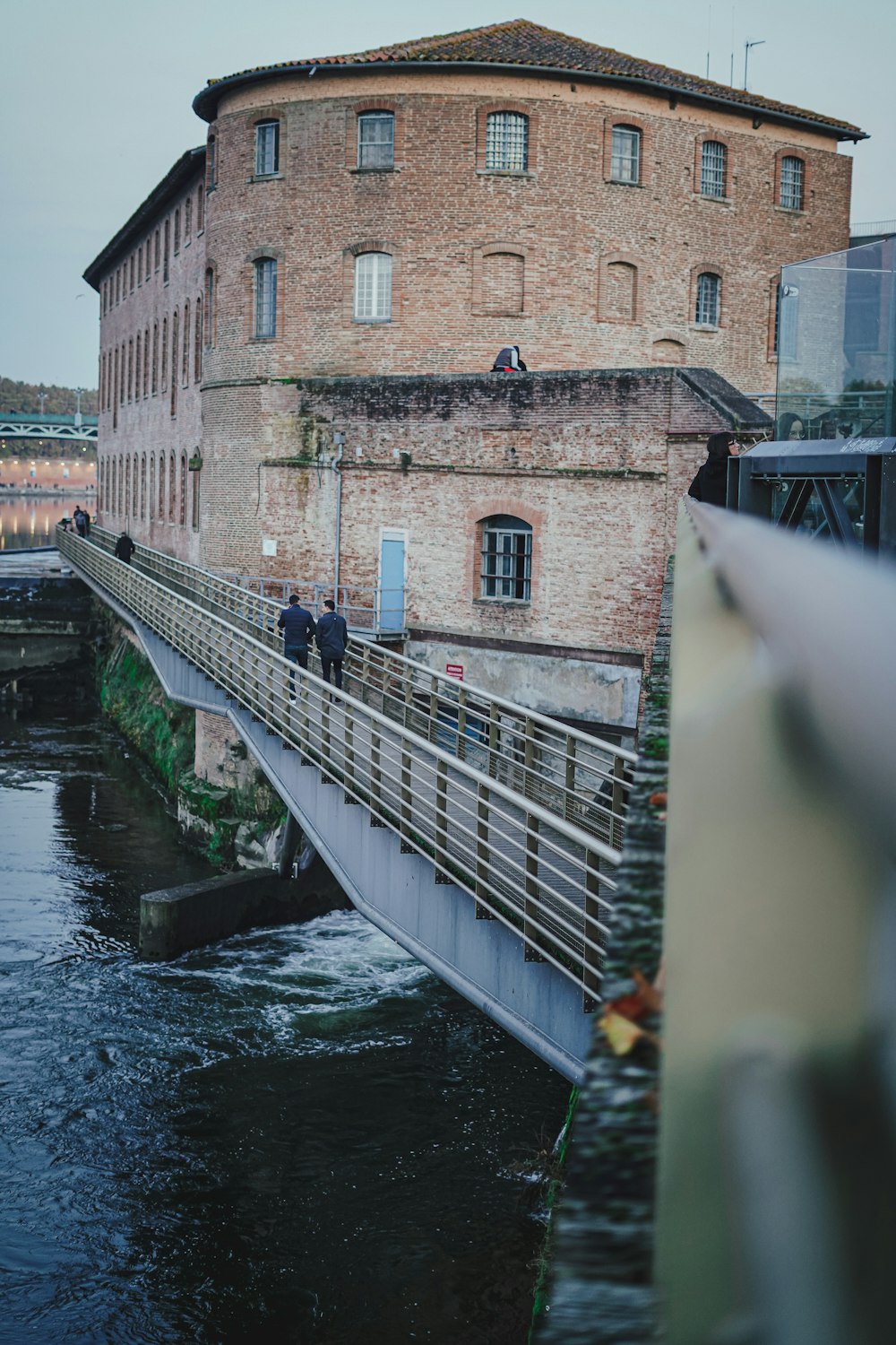 a couple of people standing on a bridge over a river