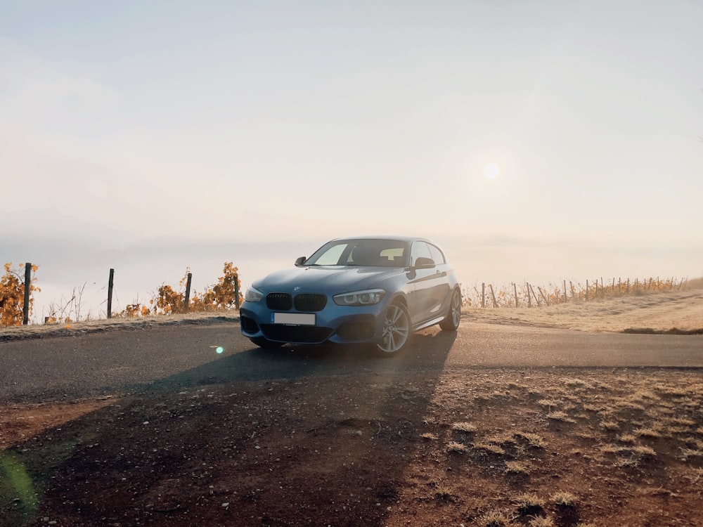 a blue car driving down a rural road