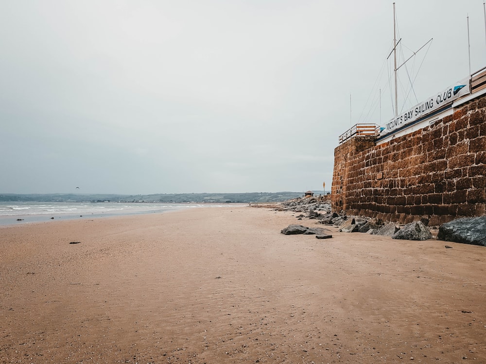 a sandy beach next to a brick wall