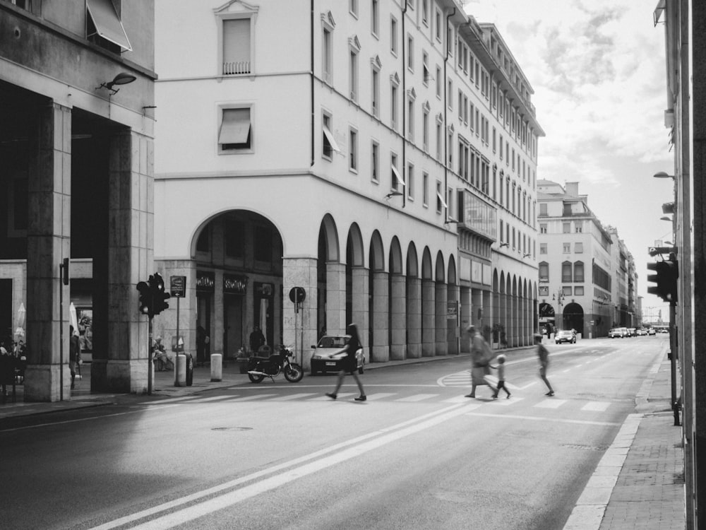 a black and white photo of people crossing the street