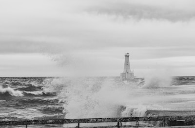 a black and white photo of a lighthouse in the ocean