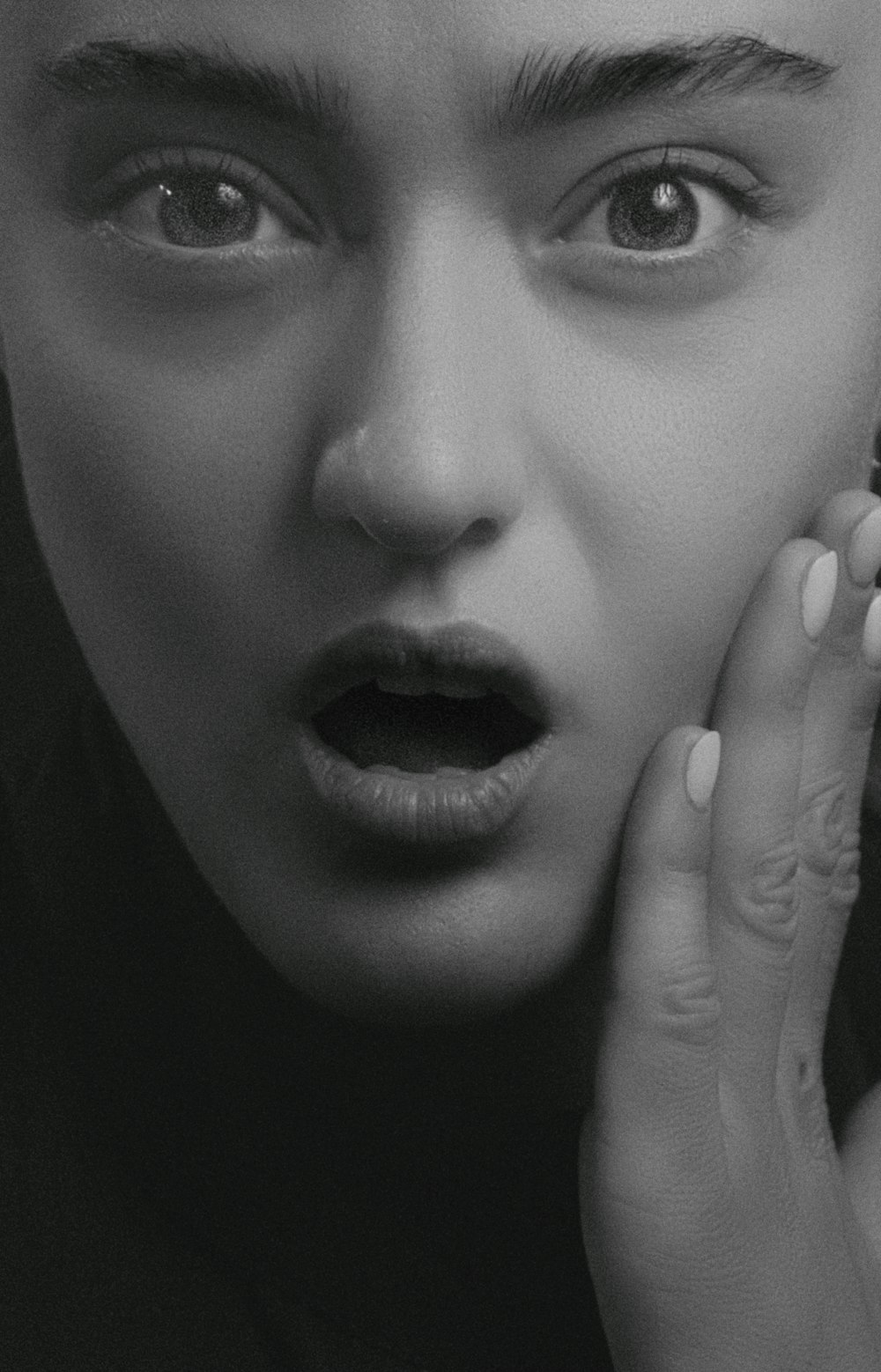 a black and white photo of a woman holding her hand to her face