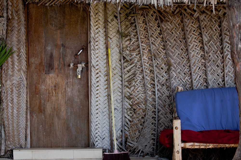 a wooden door and chair in front of a straw hut