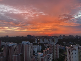 Cityscape view from a high-rise apartment balcony at sunset.