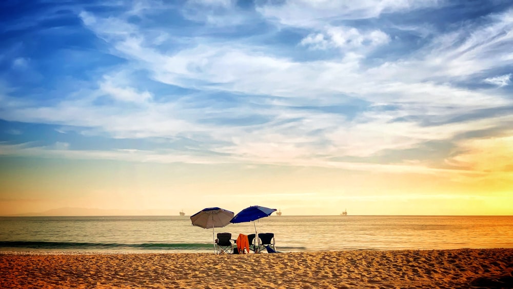 a group of people sitting under an umbrella on a beach