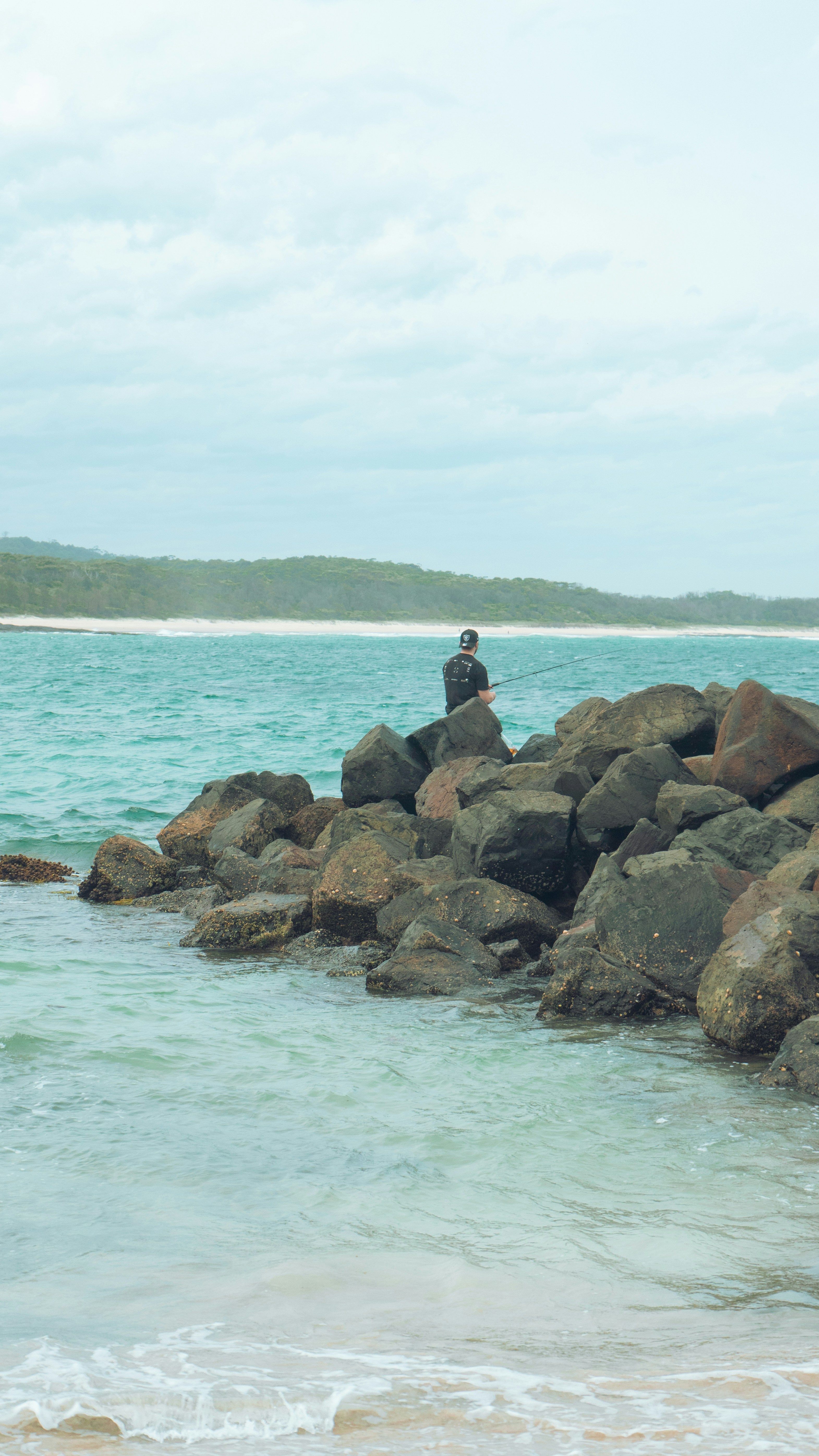 a person sitting on rocks in the ocean