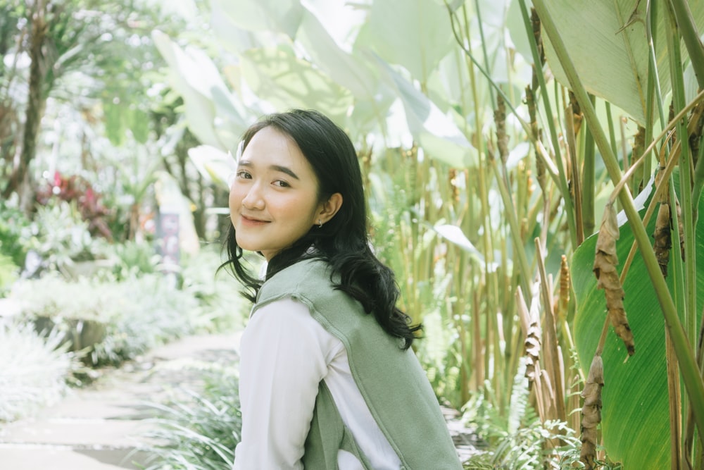 a woman standing next to a lush green forest