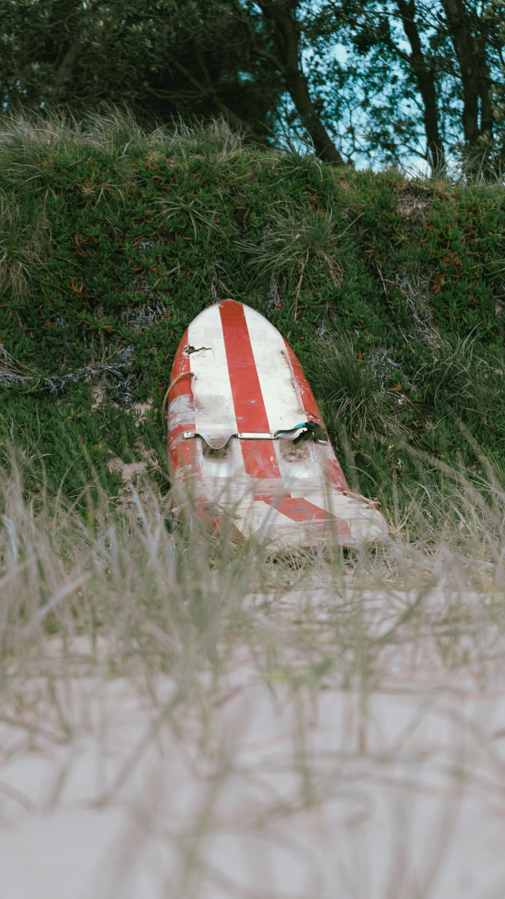 a red and white striped surfboard laying in the grass