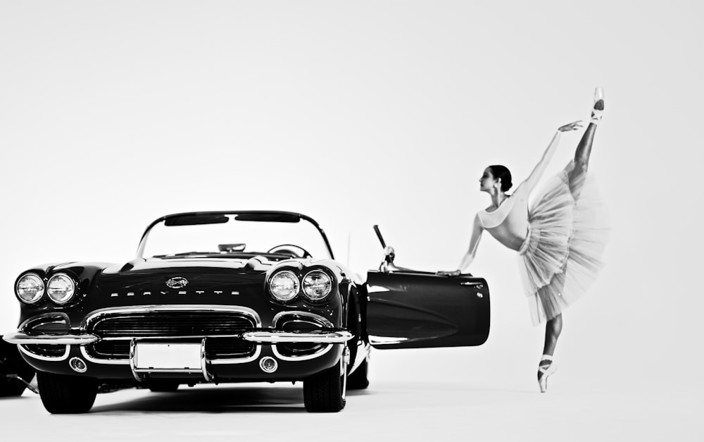 a black and white photo of a woman with a car