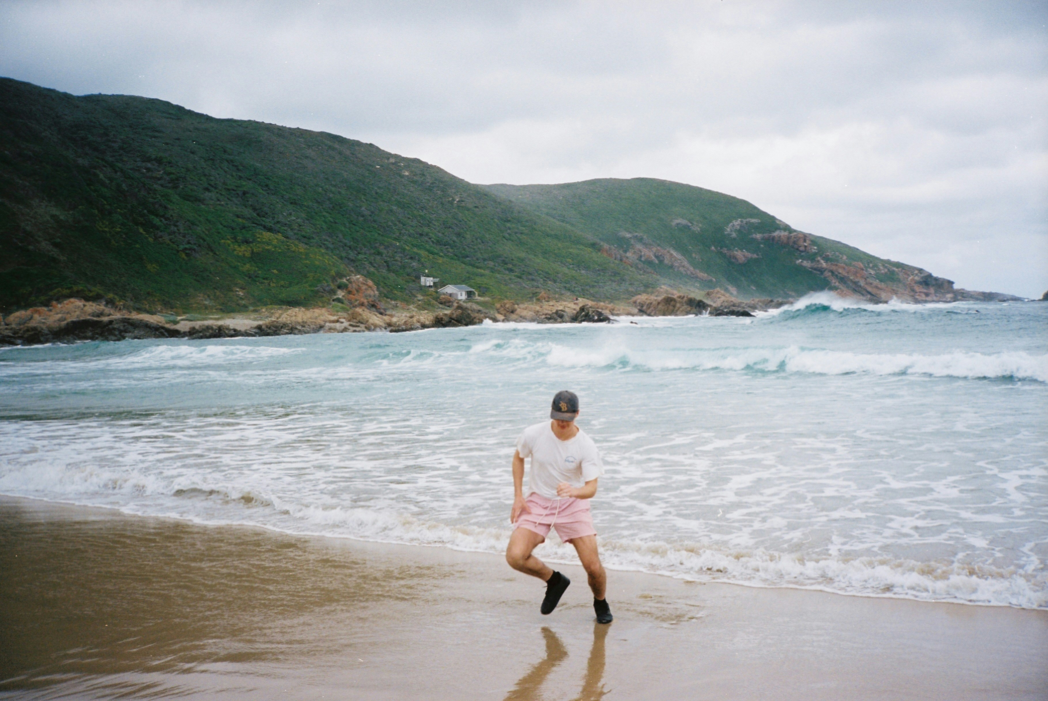 a man is running on the beach near the water