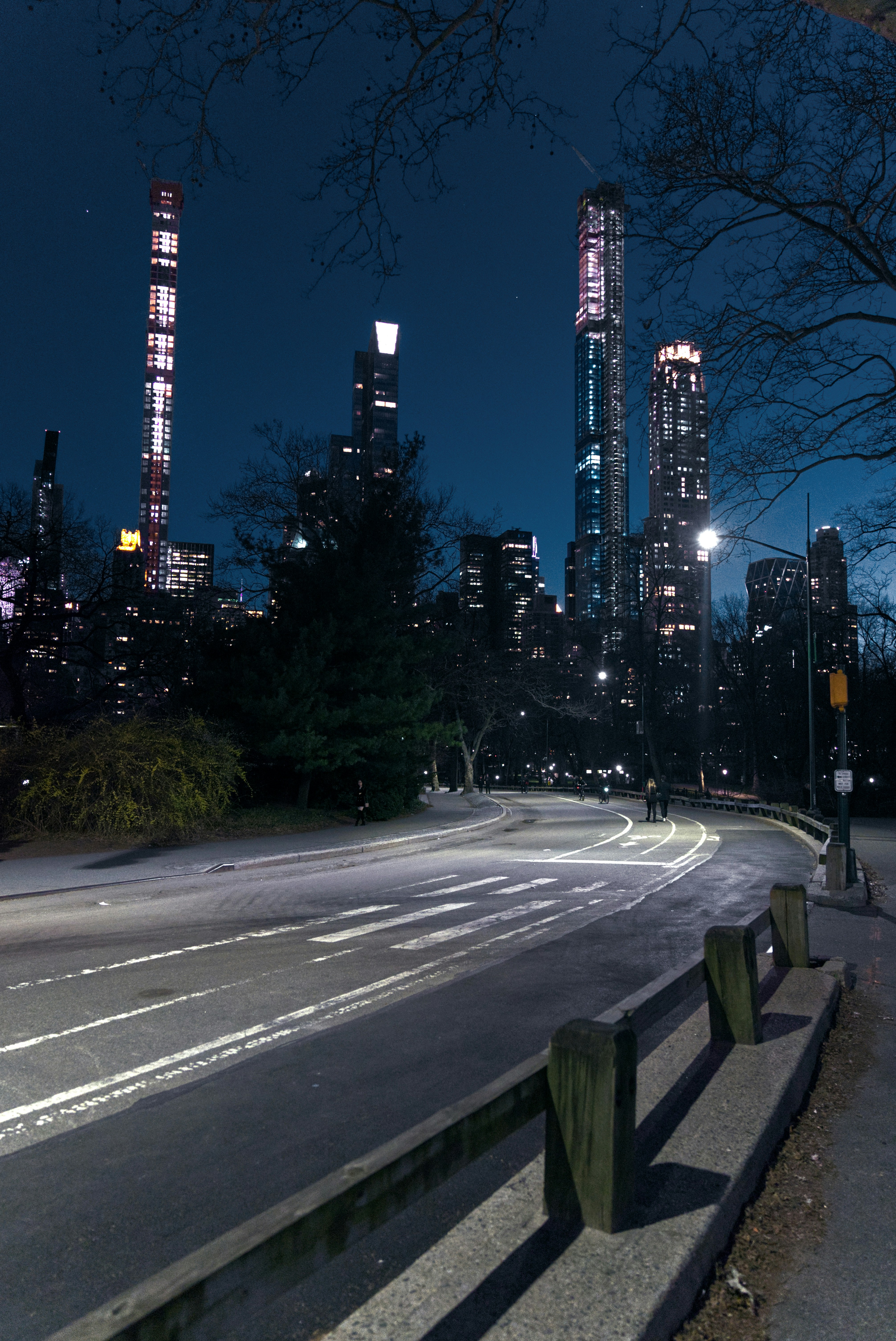 a city street at night with tall buildings in the background