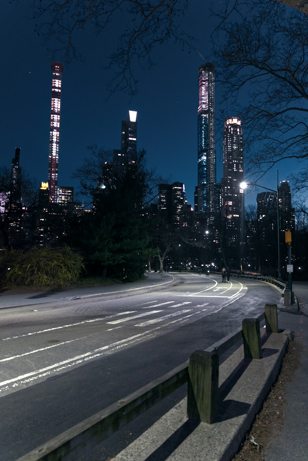 a city street at night with tall buildings in the background