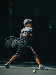 a young man holding a tennis racquet on a tennis court