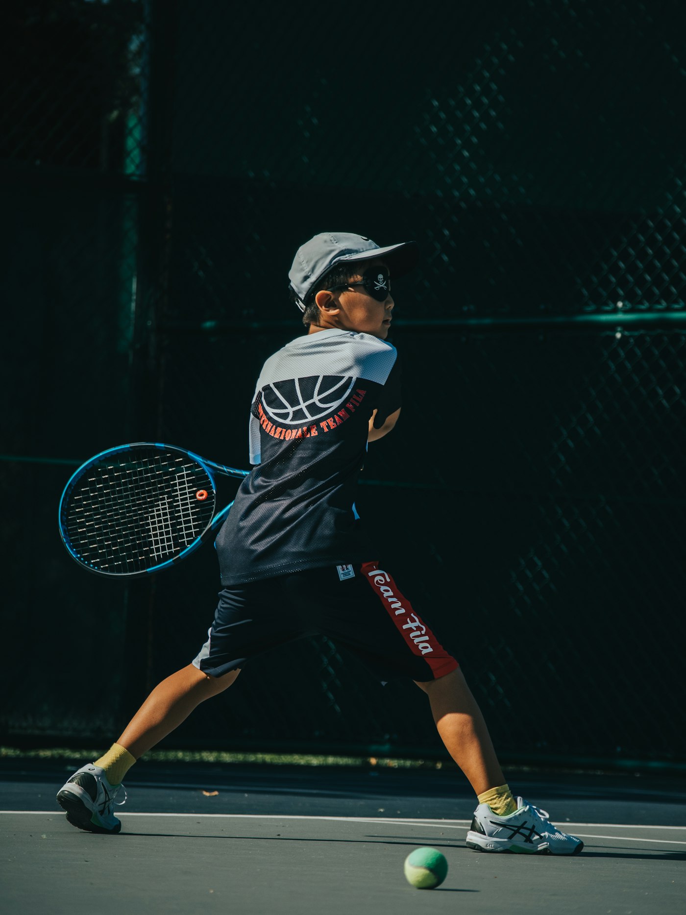 Junior tennis player practicing forehand on a hard court during training session