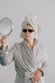 a woman with a towel on her head holding a mirror
