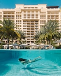 a woman swimming in a pool in front of a hotel