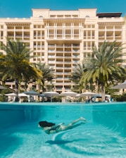 a woman swimming in a pool in front of a hotel