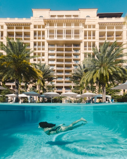 a woman swimming in a pool in front of a hotel
