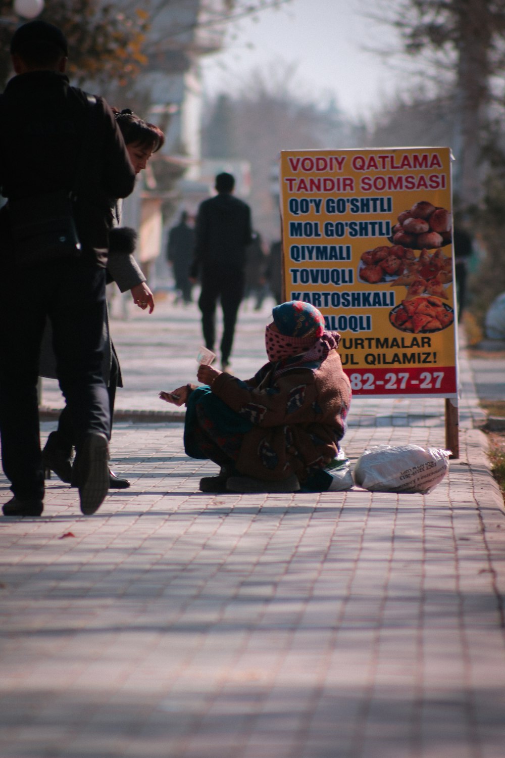 a person sitting on the ground next to a sign