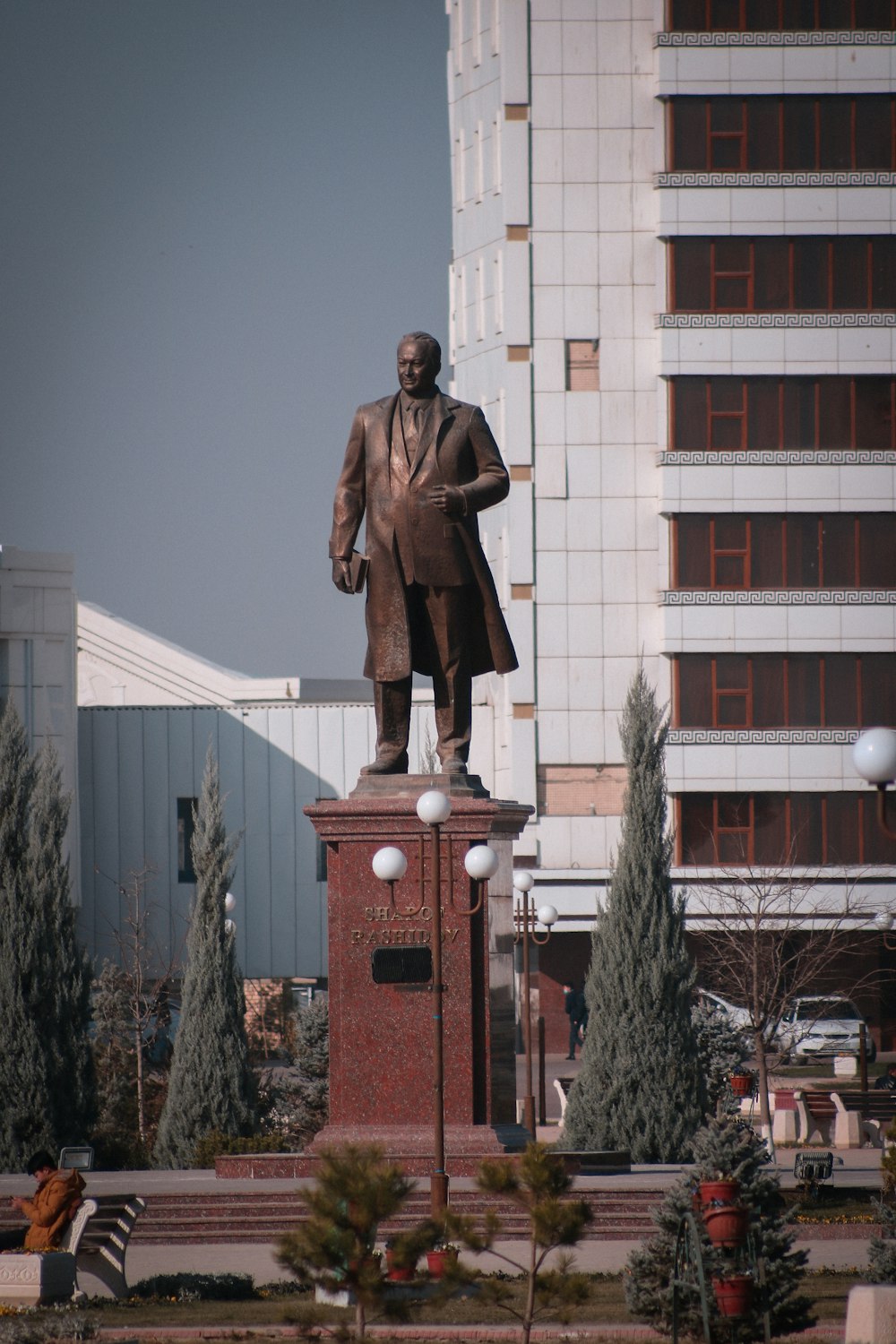 a statue of a man in a suit is in front of a building