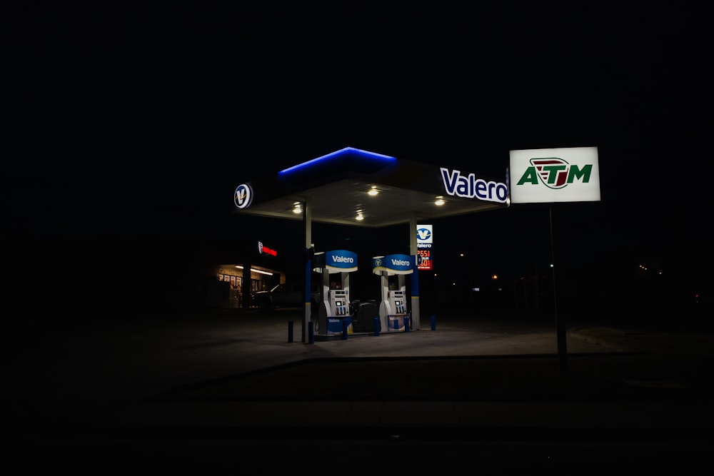 a gas station at night with a lit up sign